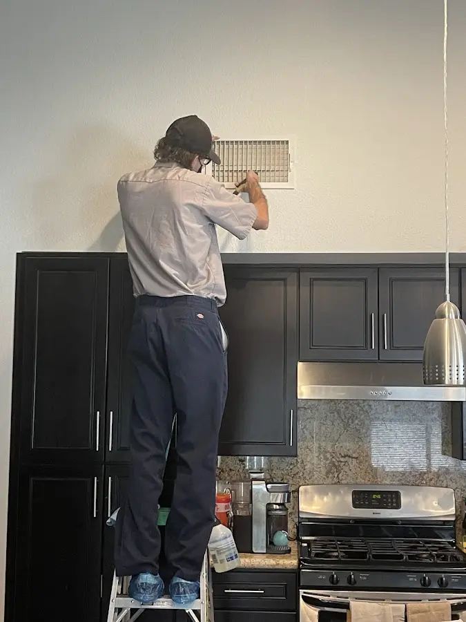 Technician inspecting an air vent during HVAC service in Fullerton